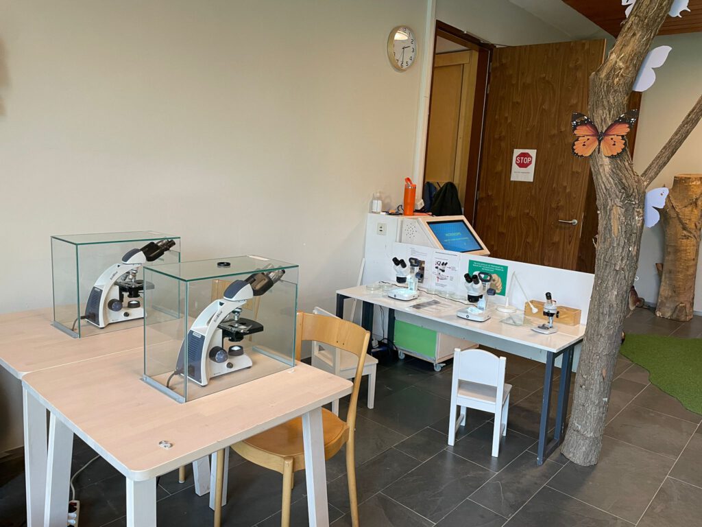 Expositie ruimte met 2 tafels met microscopen en binoculairs